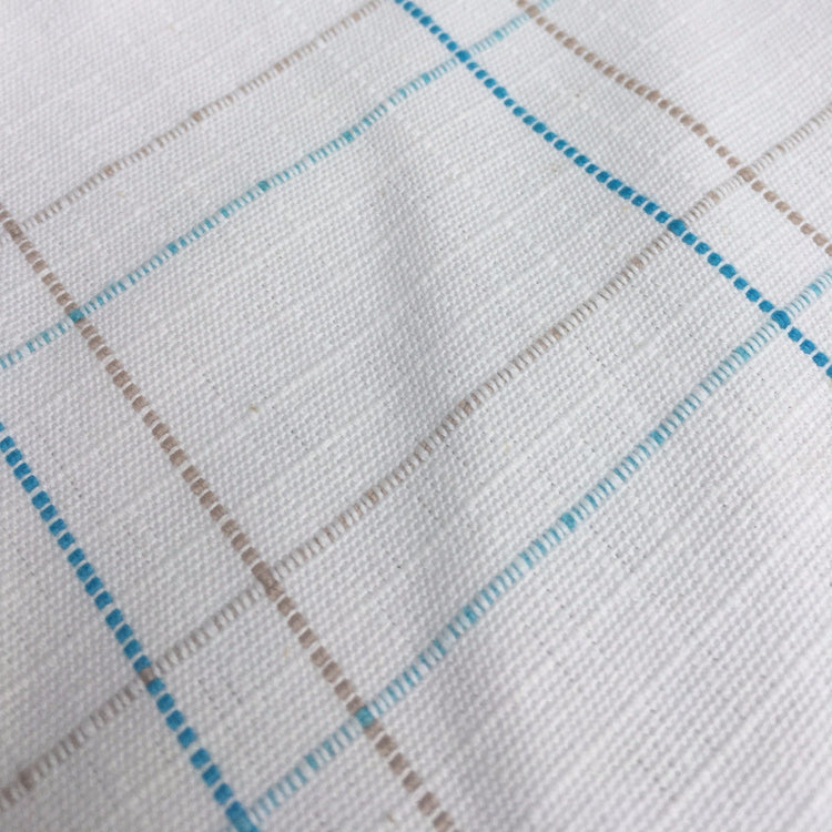 A close-up of the AniMac Allrounder Fly Rug Combo's white textured fabric, showing a subtle grid pattern with intersecting blue and beige lines. The slightly wrinkled surface adds depth, highlighting its breathable design for horses.