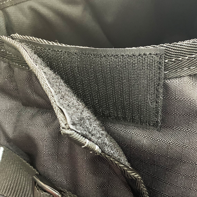 Close-up of a black fabric bag with an open Velcro closure revealing the hook-and-loop fastener, similar to that on the Super Calf Jacket | Waterproof. The stitching and material texture are clearly visible.