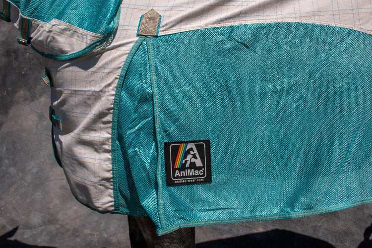 Close-up of the AniMac Allrounder Fly Rug Combo, a teal and white breathable horse rug with an AniMac patch and rainbow-striped logo, draped over a horse's back against a gray background.